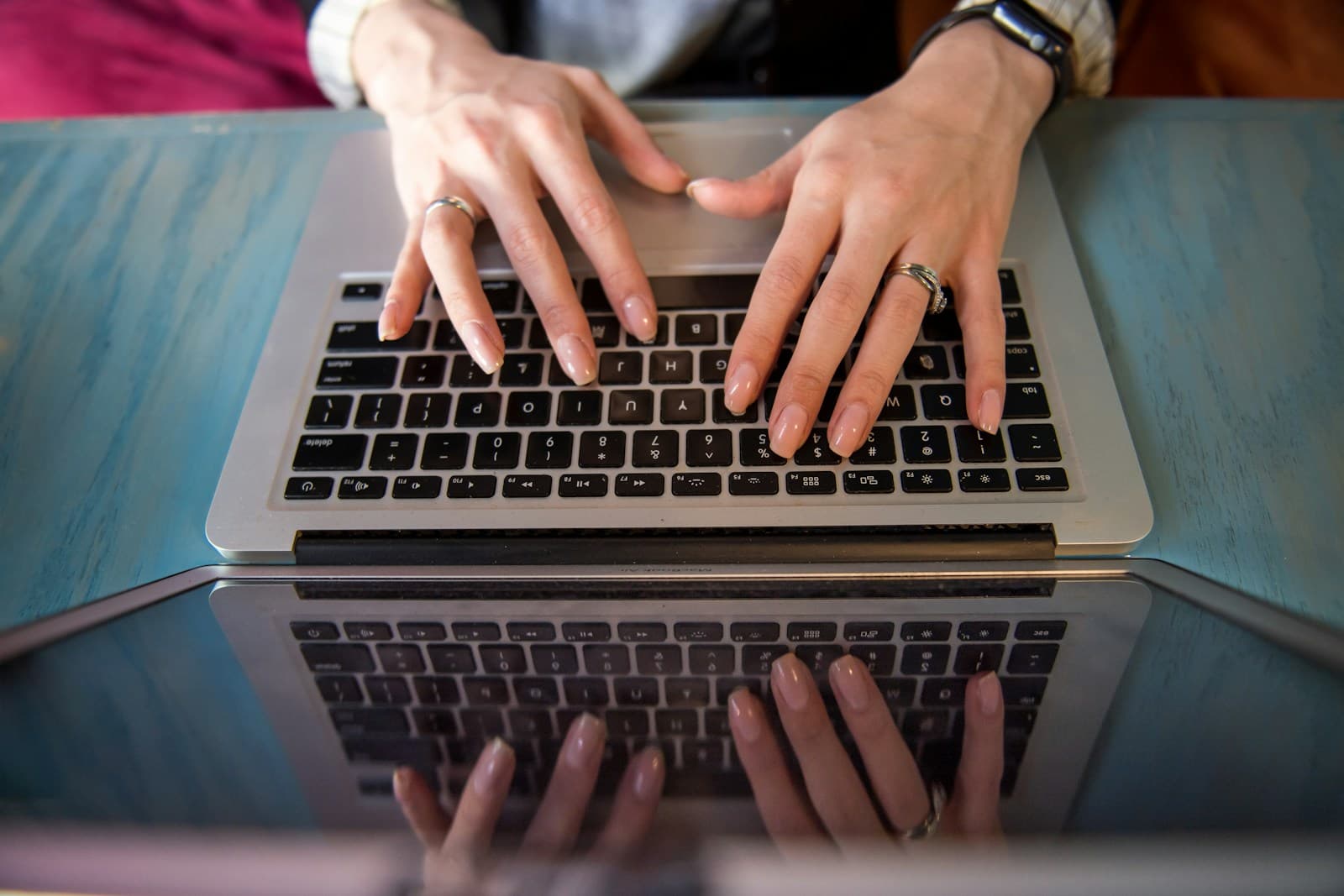 Hands typing on a laptop keyboard at a desk