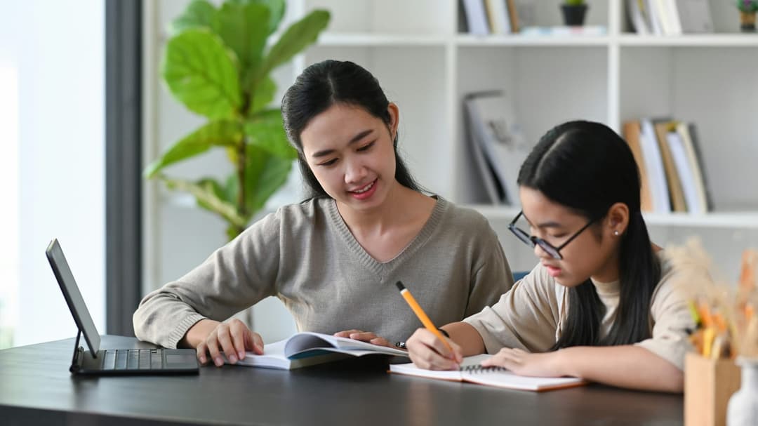 A tutor guiding a student through work at a desk